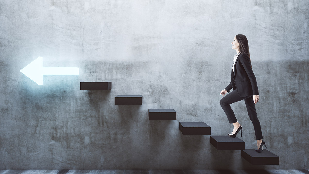 Young businesswoman walking on stairs to success with arrow on gray wall. Leadership and career development concept.