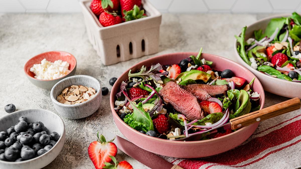 Photo of steak salad with strawberries onions avocado and greens