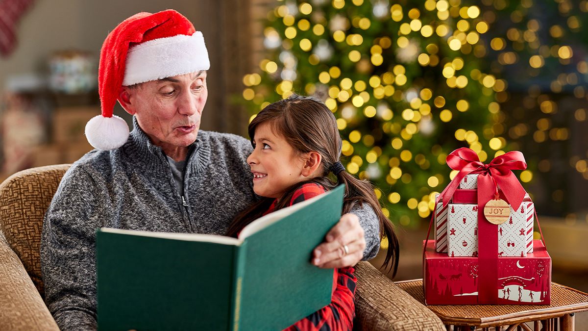 Man reading a book to young girl on Christmas eve.