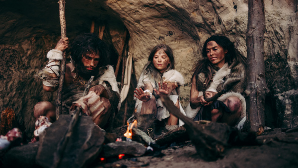 A photo of gift history with a group of cave people circle around a fire.