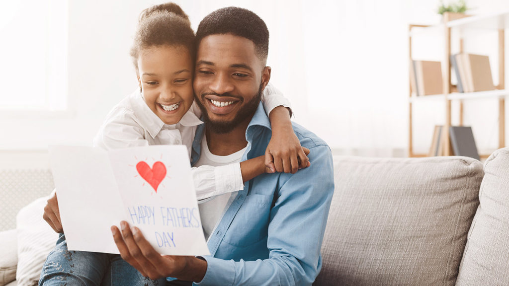 A photo of celebrate father's day with daughter giving dad a father's day card