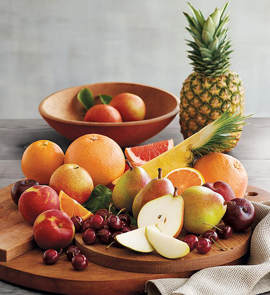 Last minute gift ideas for mom with a collection of whole and sliced fruit on a wooden cutting board.