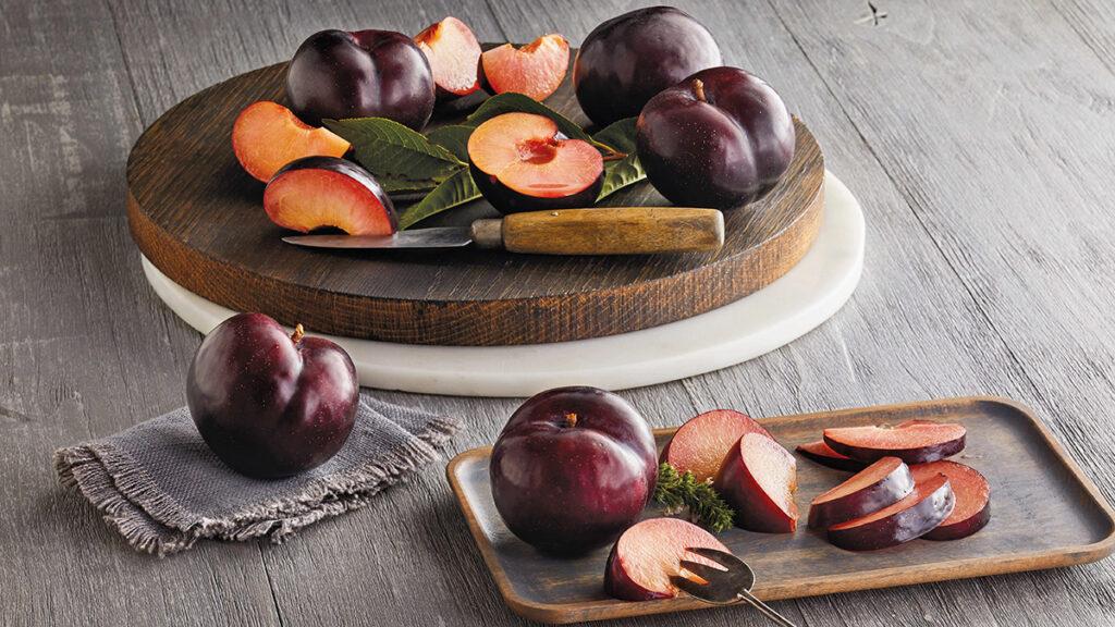 Facts about plums image   whole and sliced plums on table