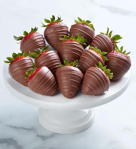 Milk chocolate covered strawberries on a platter.