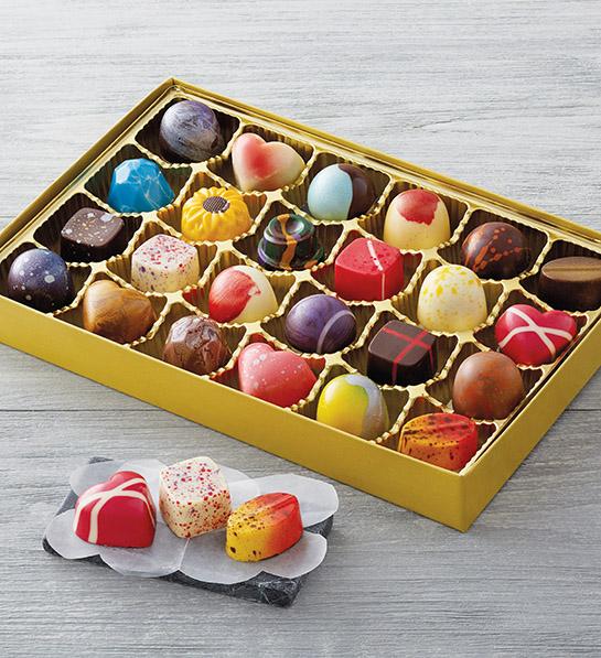 gifts for caregivers image   multicolored chocolates in a gold box with three sitting on a napkin outside and in front of the box.