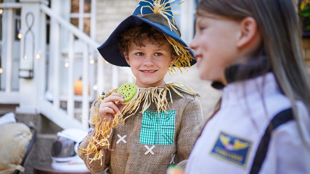 fall birthday party ideas image   child dressed as a scarecrow eating a cookie