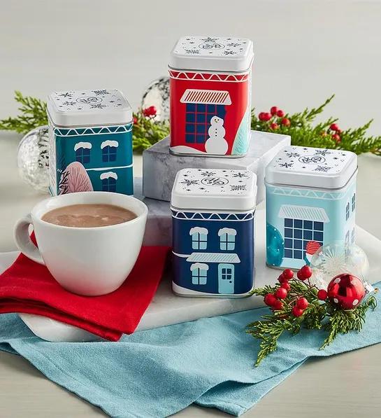 Gifts under $ with four tins of hot chocolate decorated with holiday scenes next to a mug of hot chocolate.