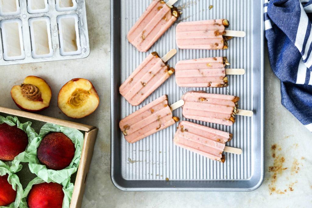 Nectarine fruit popsicles on a tray next to a crate of nectarines.