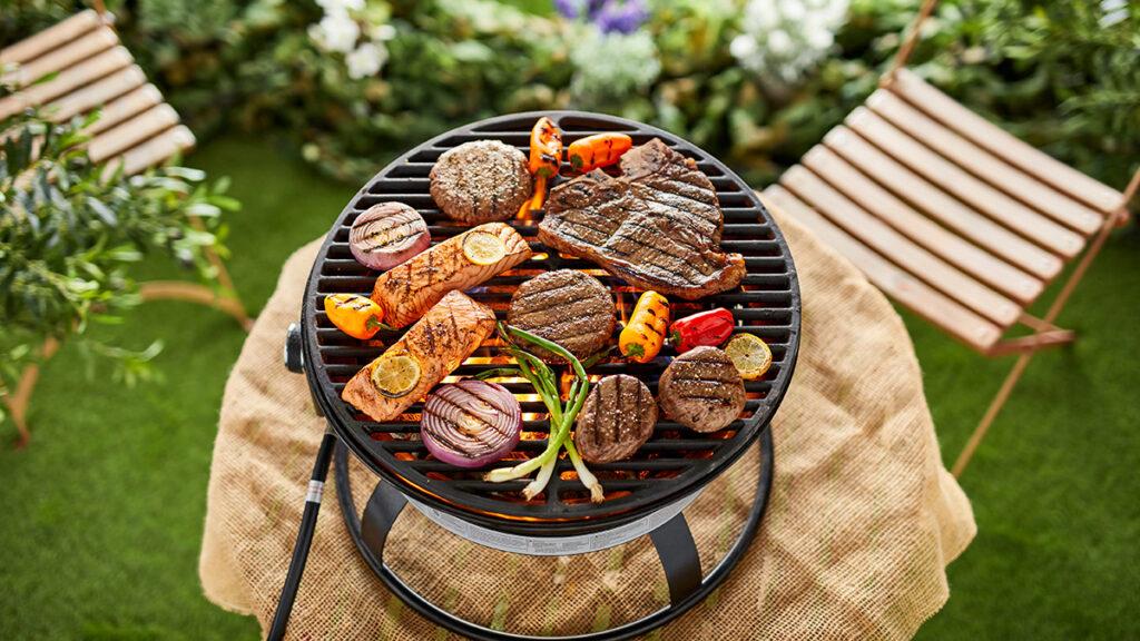 Summer grilling outside with different types of meat and vegetables on a grill.
