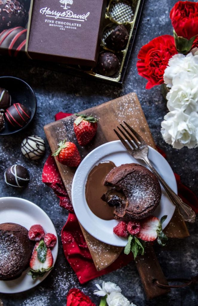 Valentines Day dessert ideas with a two chocolate lava cakes on plates surrounded by strawberries and truffles