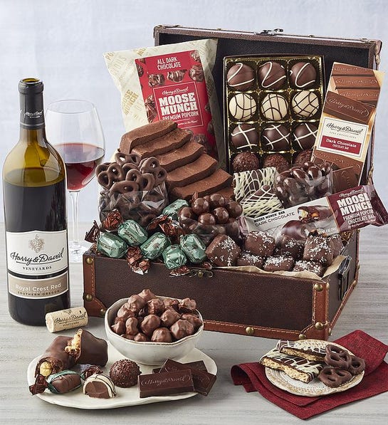 A photo of birthday gift ideas with a box of chocolate truffles cake and other snacks next to a bottle of wine