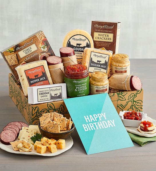 A photo of birthday gift ideas with a box full of cheese meat and other snacks with a plate of the same items in front of the box next to a card that says happy birthday