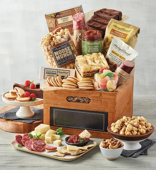 Best gift basket full of sweet and savory snacks surrounded by the same items on plates and platters