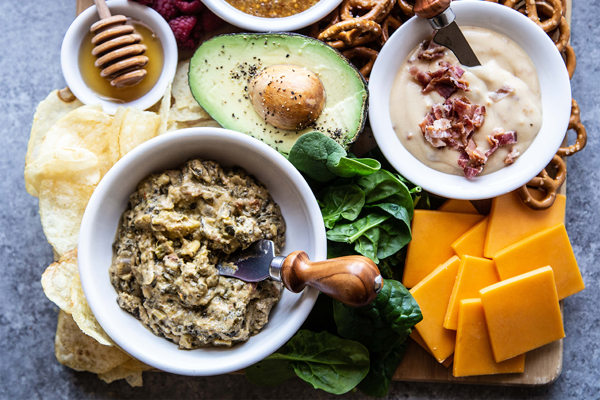 Game day snack board from above with dips, vegetables, snacks and other items.