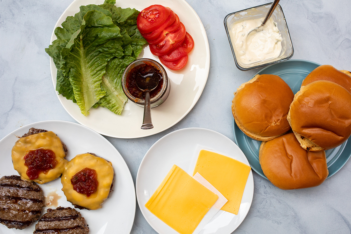 Grill burgers toppings on plates.