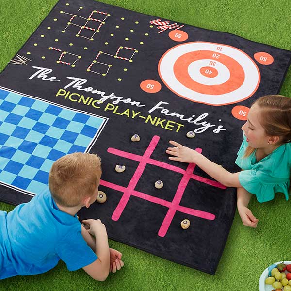 A photo of birthday gift ideas with a blanket with different game designs and two children playing tic tac toe on the blanket