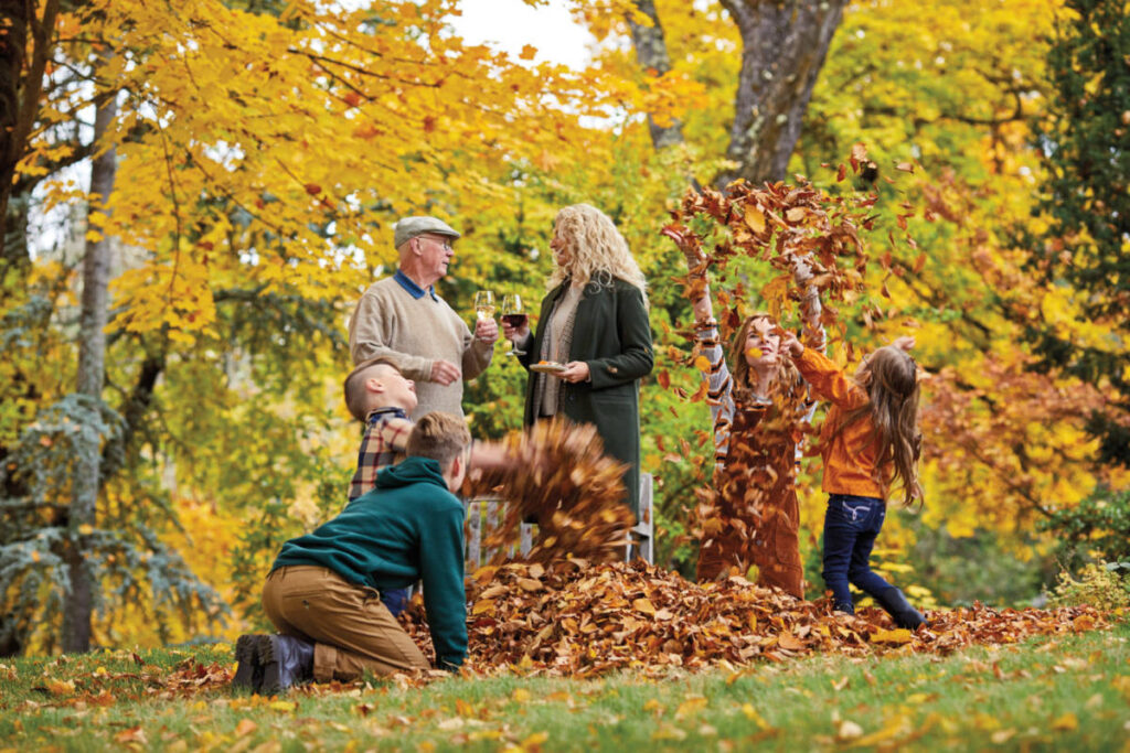 fall leaves image   kids playing in leaves with two adults in the background