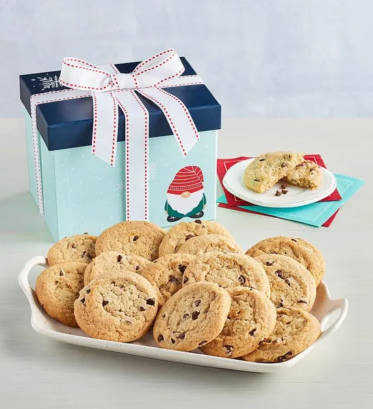 Gifts under  with a Christmas decorated box next to a plate of chocolate chip cookies