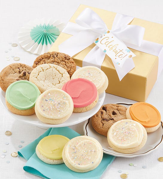 A photo of birthday gift ideas with two plates of cookies in front of a gold box with a white ribbon