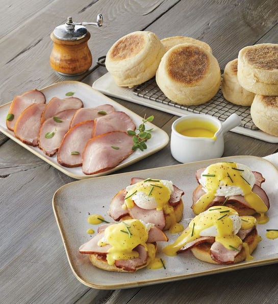 A photo of birthday gift ideas with a plate of eggs Benedict with the ingredients for eggs Benedict on plates behind it