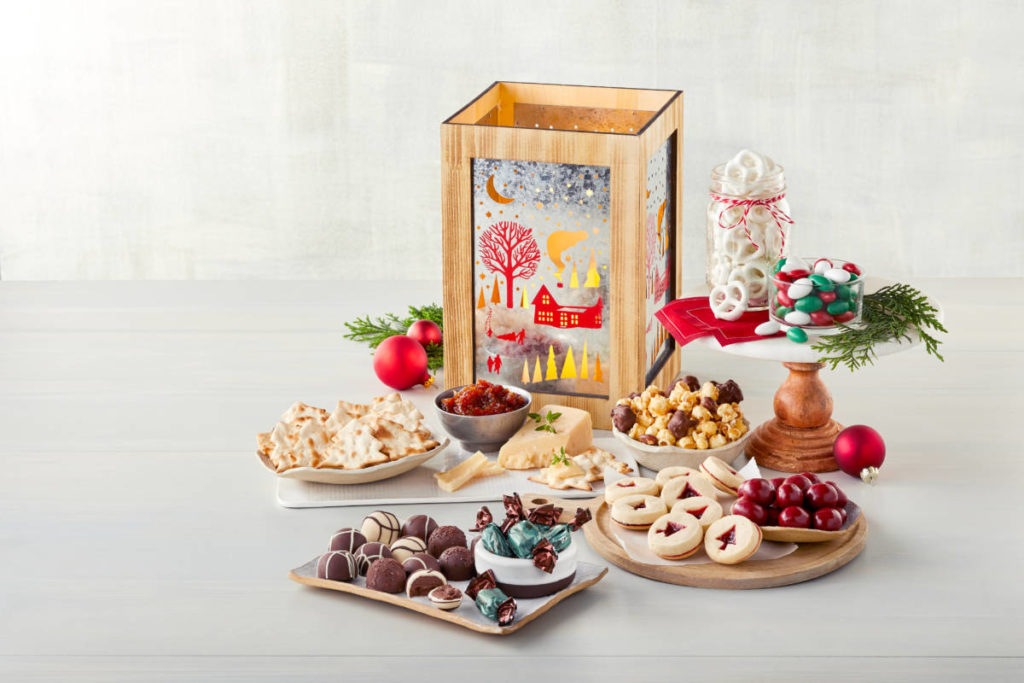 A photo of a holiday lantern surrounded by cookies cheese crackers and truffles