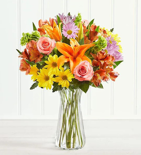 A photo of birthday gifts for sister with a bouquet of flowers in a clear vase