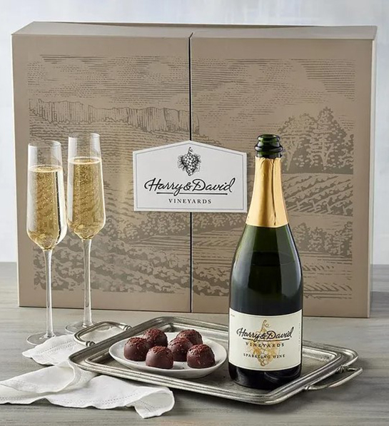 A photo of graduation gift ideas with two glasses of sparkling wine next to a platter of truffles and a bottle of sparkling wine