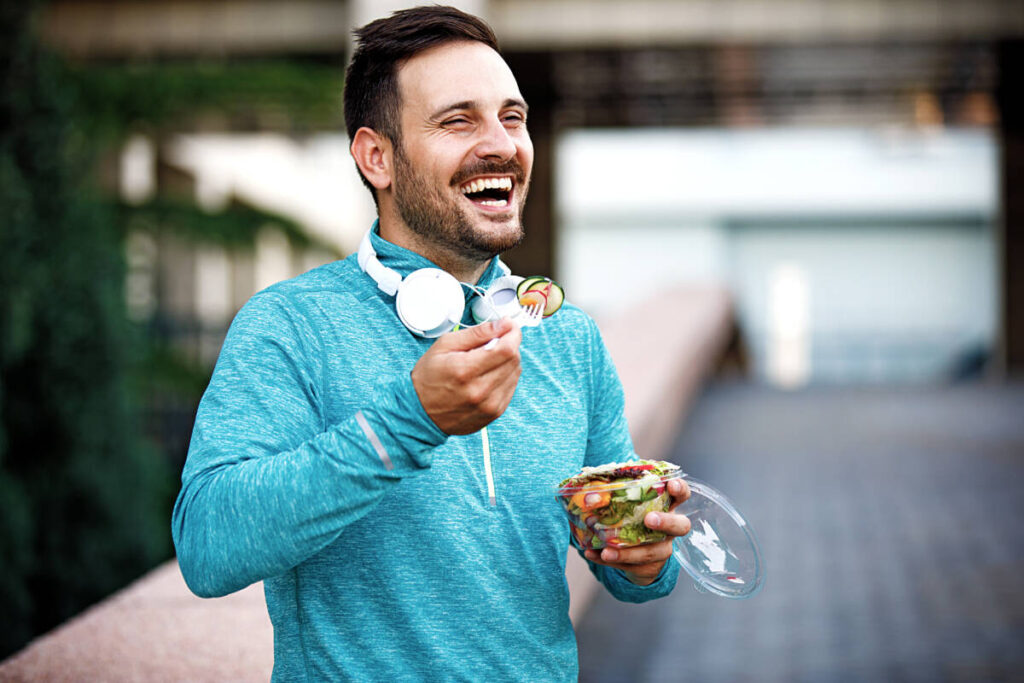 new years resolutions young handsome man is enjoying vegetable salad after jogging.