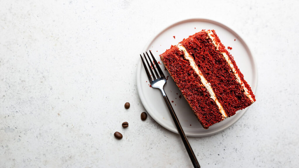 History of red velvet cake with a piece of red velvet cake on a plate.