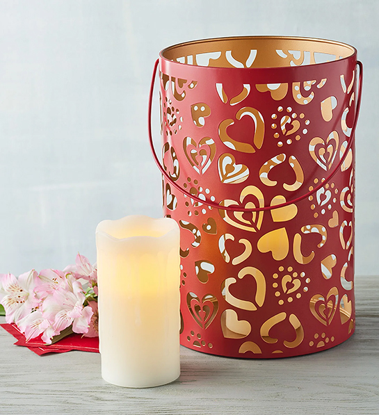 Valentines Day gifts for her with a red tin lantern with cutout hearts next to an electric candle