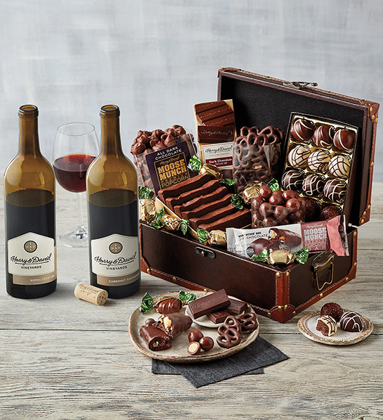 Valentines Day gift ideas for him with a chest of chocolate goodies next to two bottles of wine