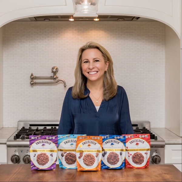 Undercover Snacks founder standing at a table with bags of Undercover Snacks.