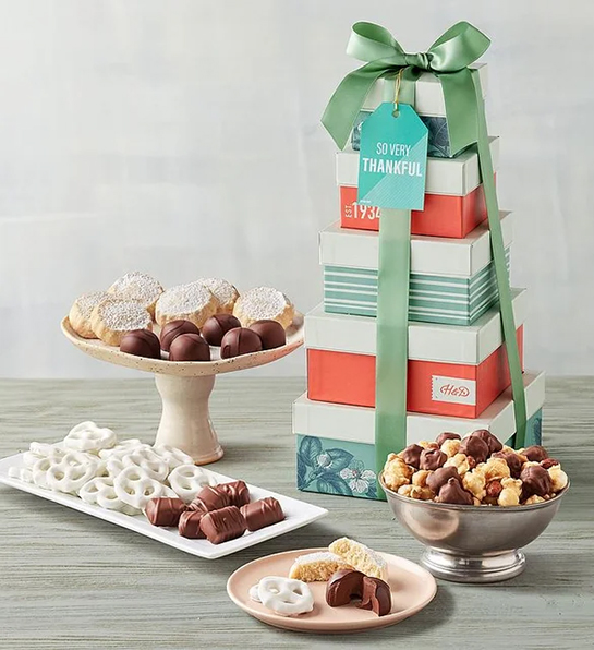 Unique thank you gifts with a tower of gift boxes next to an array of chocolates cookies and Moose Munch