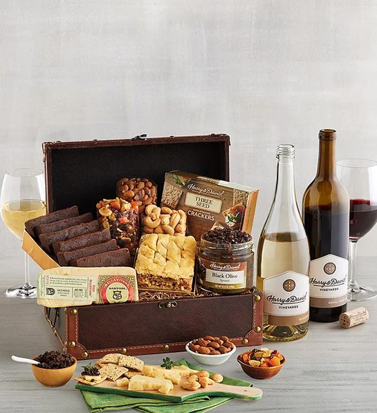 Unique thank you gifts with a chest of sweet and savory treats next to two bottles of wine