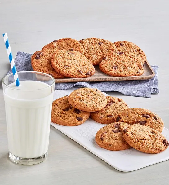 Gluten free cakes with plates of cookies next to a glass of milk