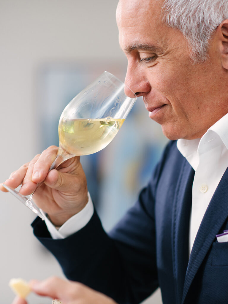 Geoffrey Zakarian sniffing a glass of chardonnay.