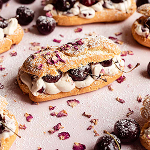 Several cherry eclairs on a pink counter top