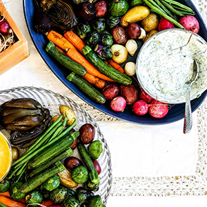 Roasted summer squash and other vegetables on a platter with yogurt dip