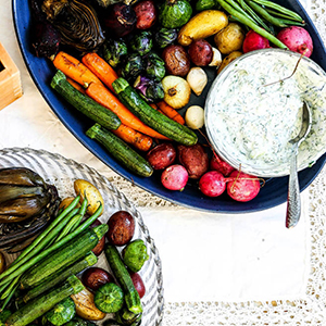 Roasted carrots and other vegetables with a bowl of yogurt dip