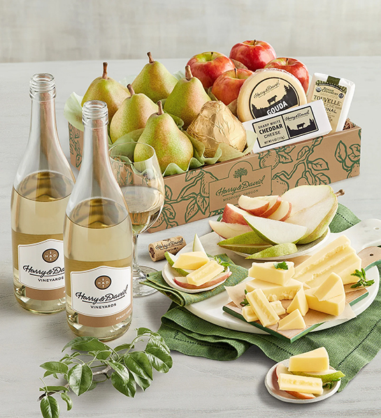 Cheese gifts with a box of pears apples and cheese next to two bottles of white wine