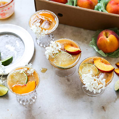 Peach margaritas with elderflower garnish