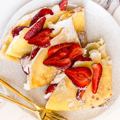 Breakfast for dinner with a plate of crpes topped with strawberries