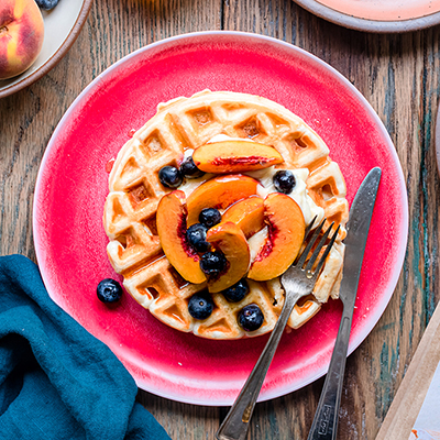 Breakfast for dinner with a plate of waffles topped with fruit