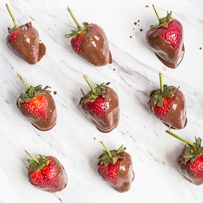 Rows of chocolate covered strawberries on a marble counter