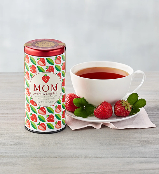 Strawberry tea tin next to a cup of tea for a tea party