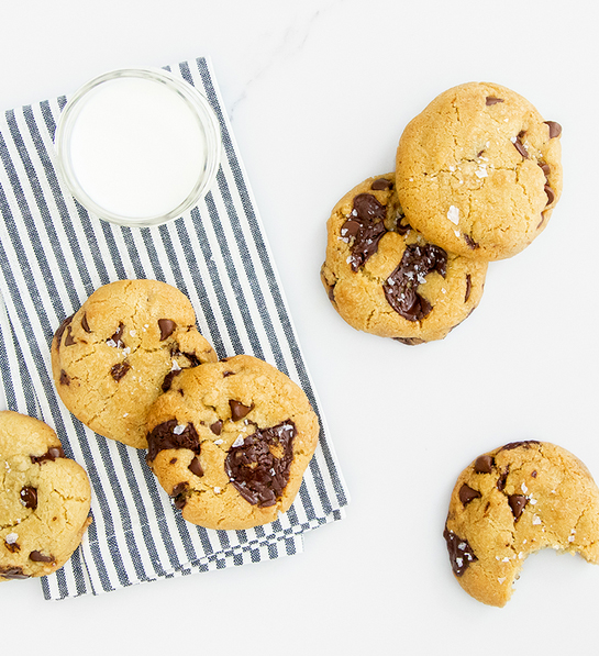 Gifts for the home cook with several chocolate chip cookies on a stripped napkin