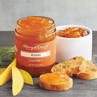 Jar of mango chutney next to slices of mango